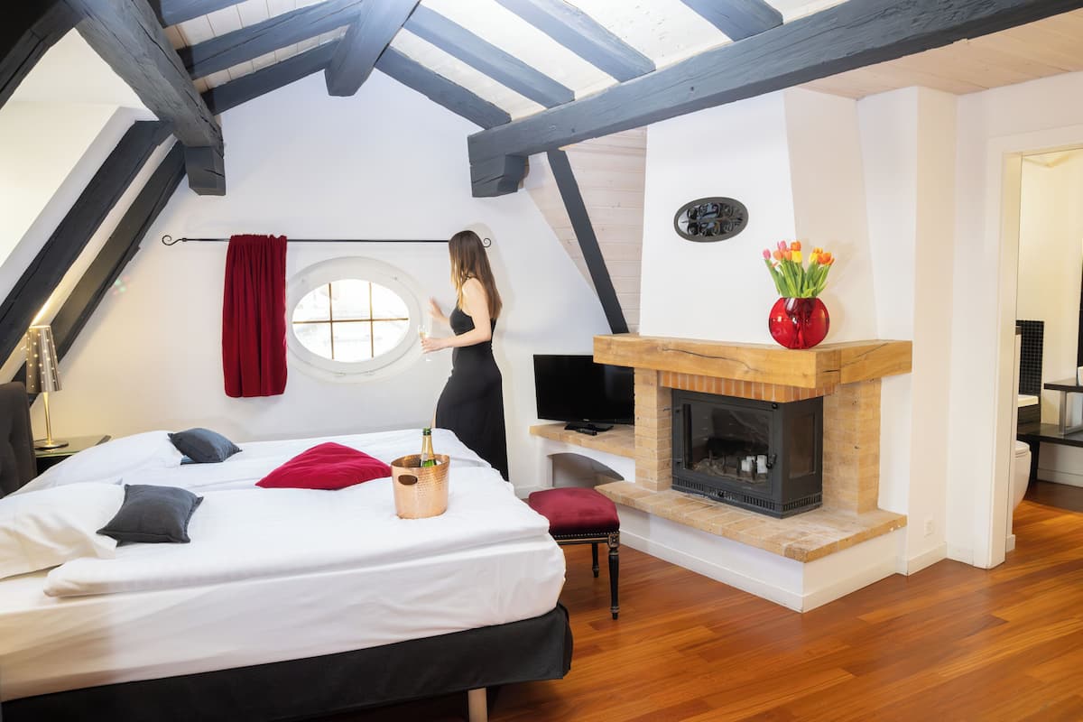 A bedroom with a bed, a red curtain, a fireplace, and a TV.