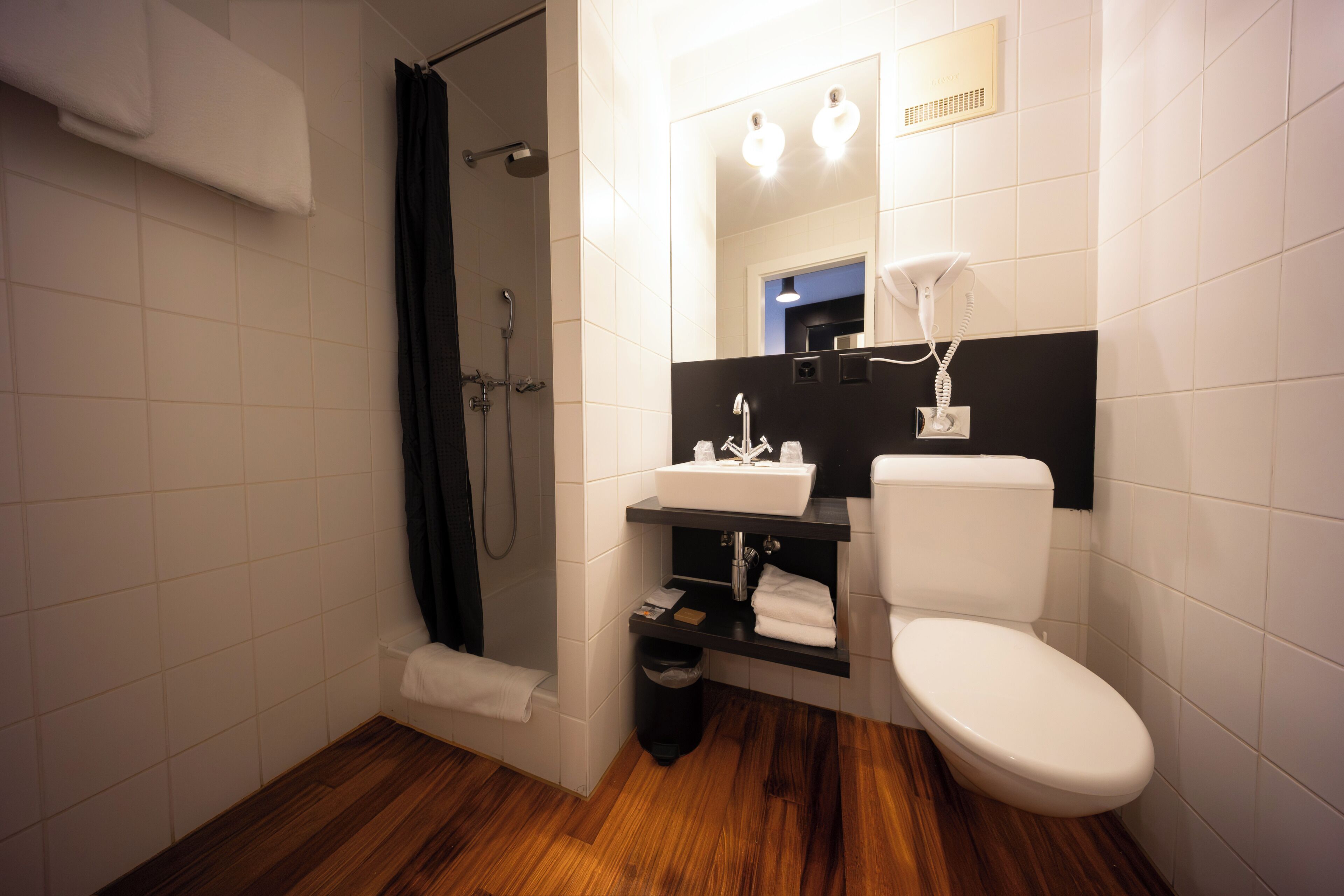 Une salle de bain équipée d’une douche, de toilettes, d’un lavabo et d’un miroir.
