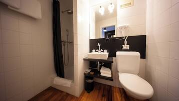 Une salle de bain équipée d’une douche, de toilettes, d’un lavabo et d’un miroir.