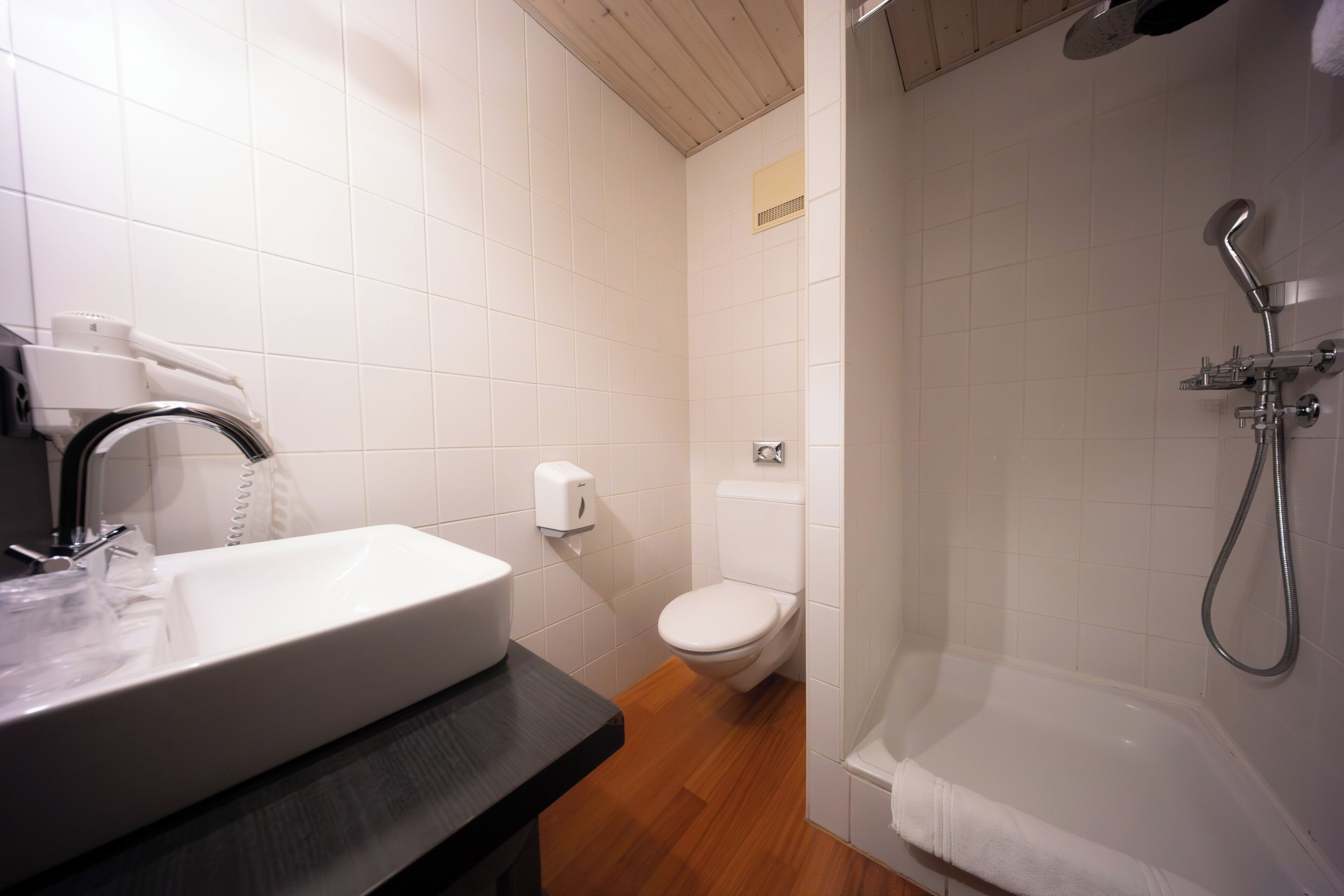 Un baño con lavamanos, inodoro y ducha blancos.