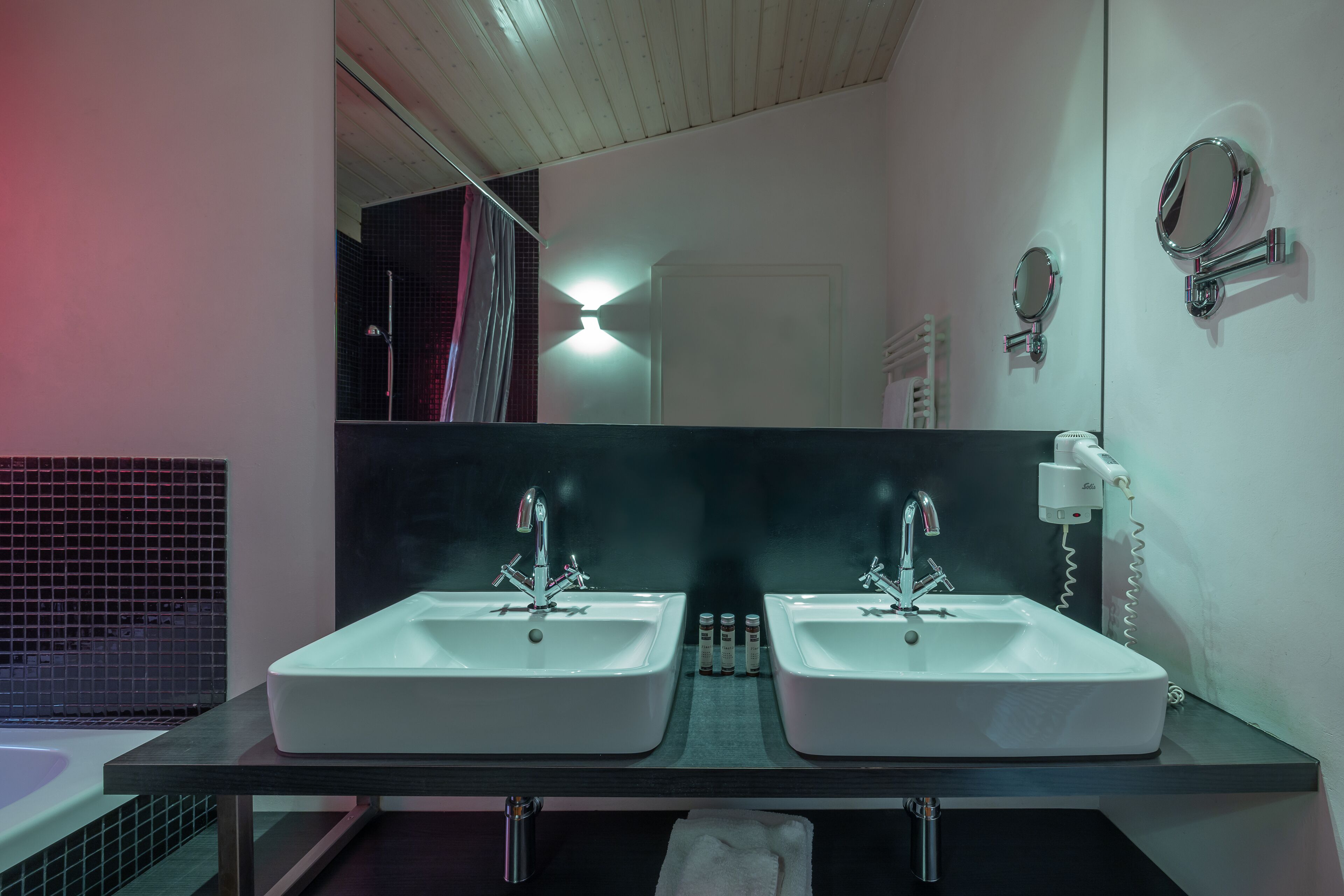 A bathroom with two sinks, a mirror, and a towel rack.