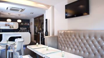 Eine moderne Bar mit Theke, Sitzgelegenheiten und einem an der Wand befestigten Fernseher.