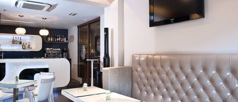 Een moderne bar met een toonbank, zitplaatsen en een televisie aan de muur.