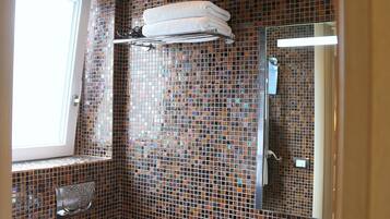 Un bagno con una parete in mosaico, un water, un lavandino e una finestra.