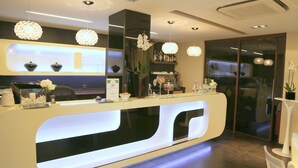 A modern reception desk with a glass top, white and black color scheme, and decorative lighting.