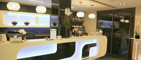 En moderne receptionsdisk med glasplade, i hvid og sort farve, og dekorativ belysning.