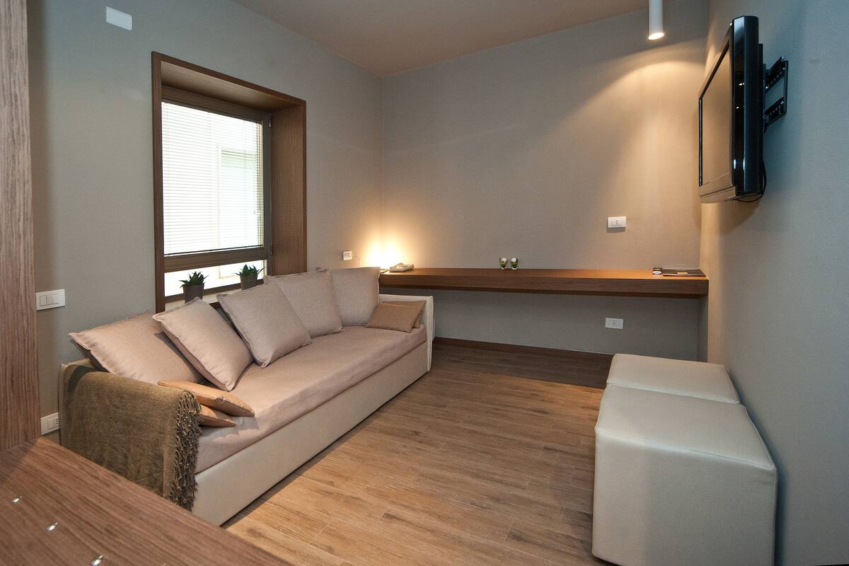 Una habitación moderna con sofá, una mesita y un televisor montado en la pared.