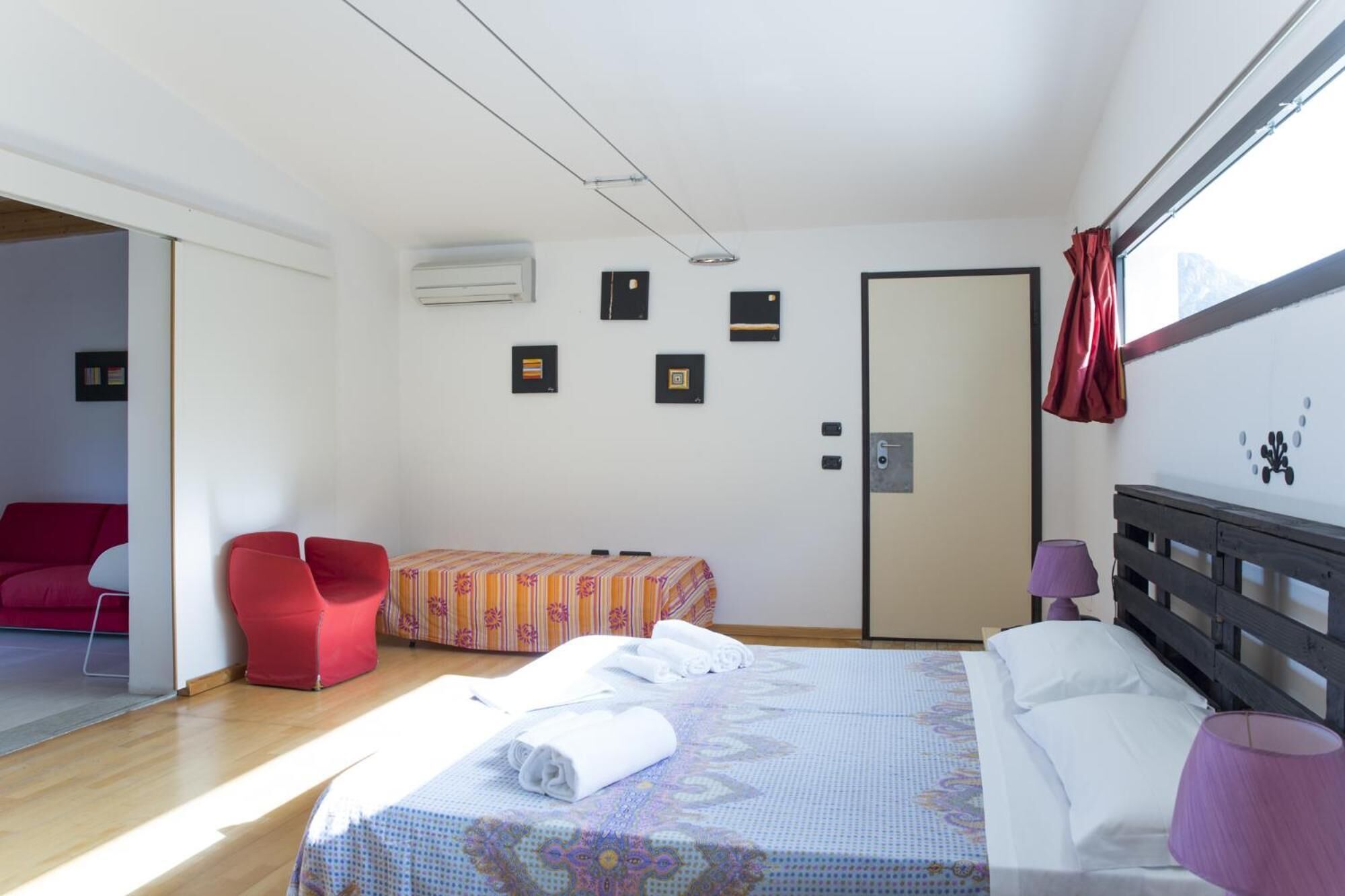 A hotel room with a bed, a chair, a small table, and a door.