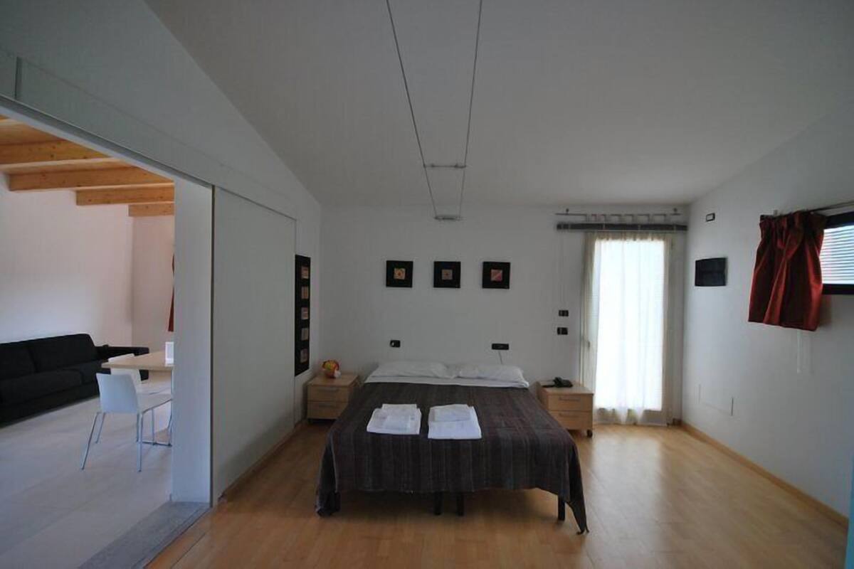 A bedroom with a bed, bedside tables, a desk, and a chair.