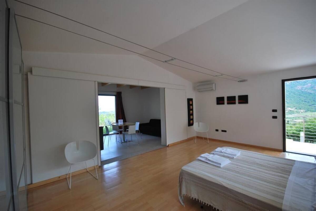 A modern hotel room with a bed, a dining area, and a view of the outdoors.