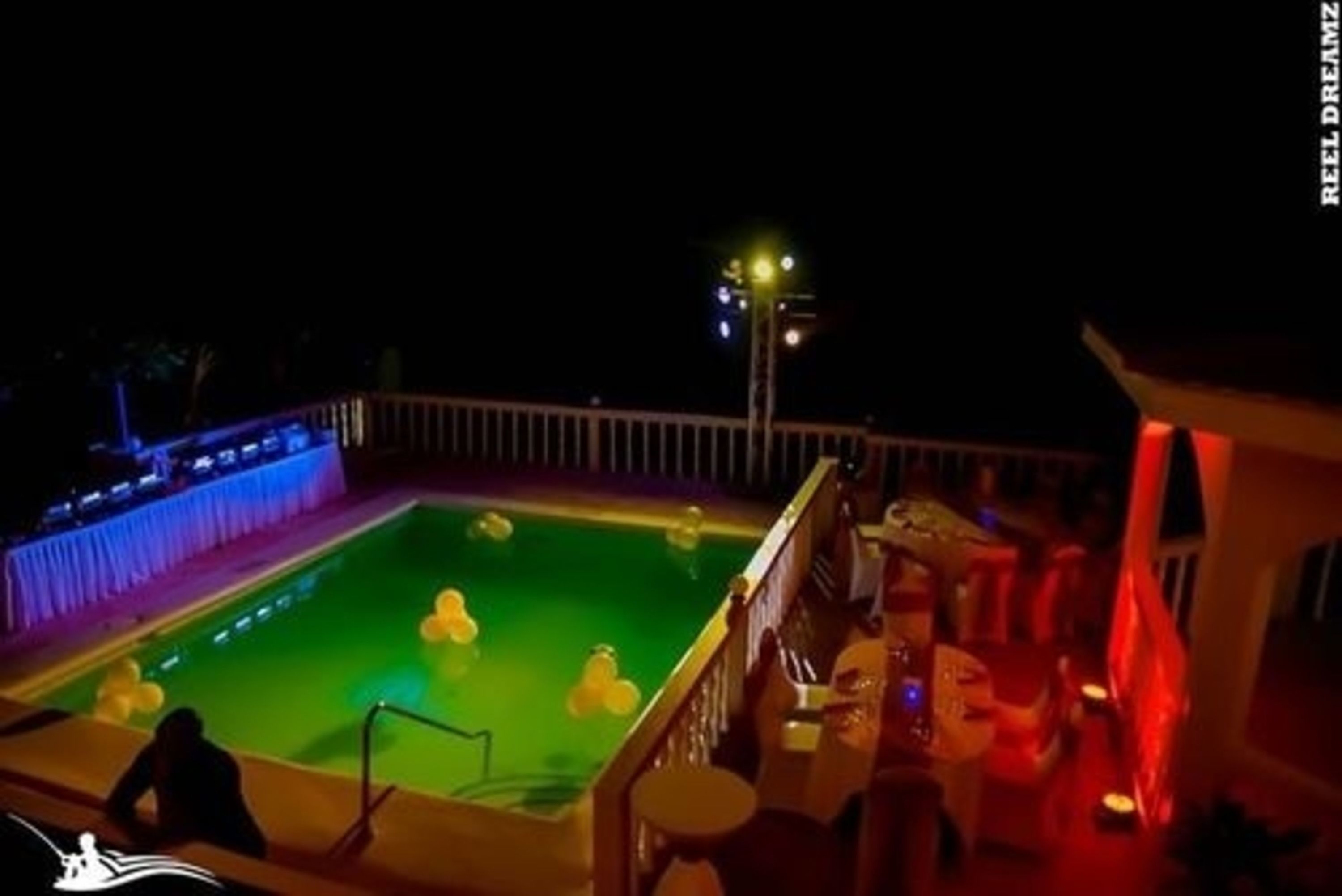 A pool area with a water feature and a bar area with stools and a table.