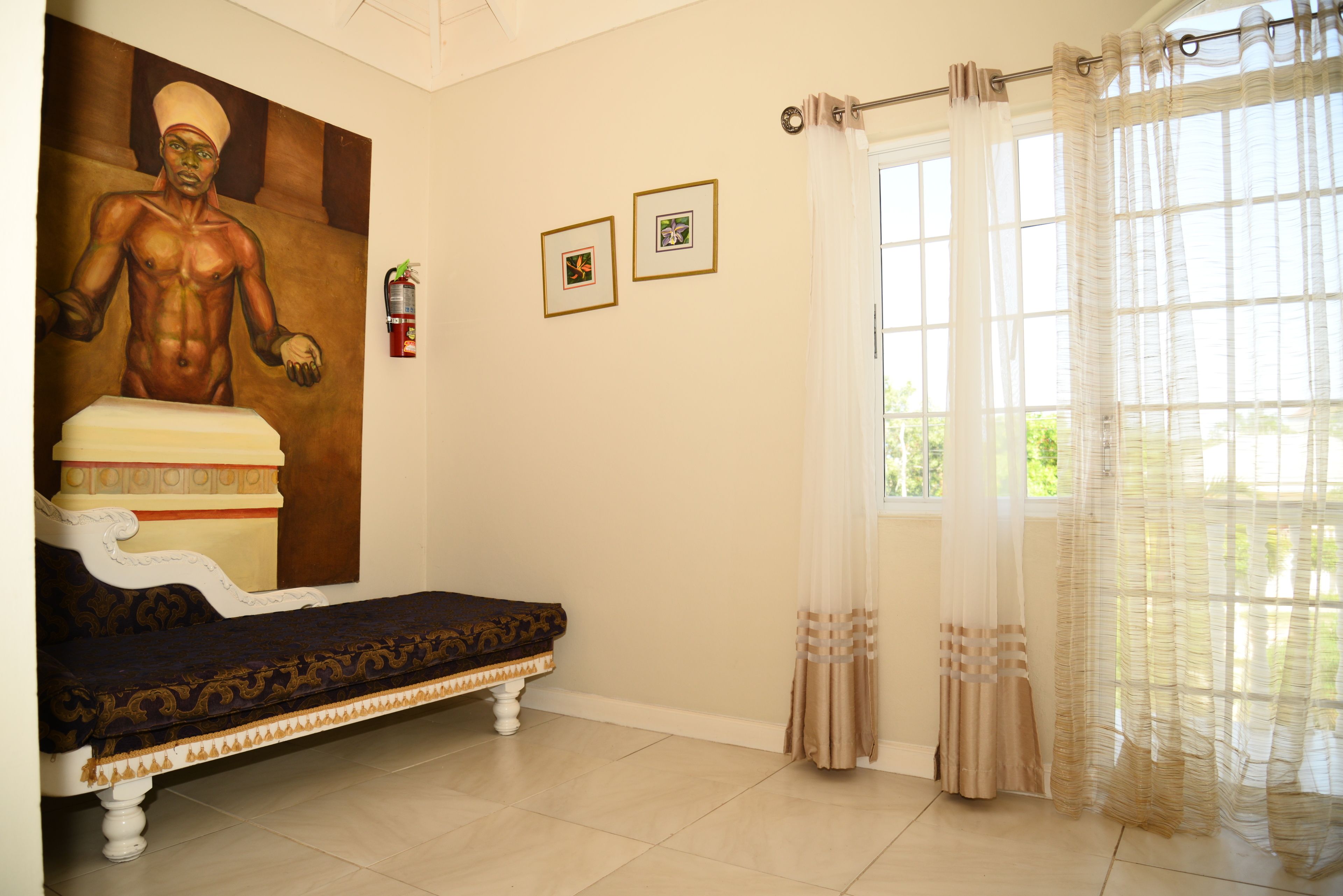 A room with a bed, a large painting, and two framed pictures on the wall.