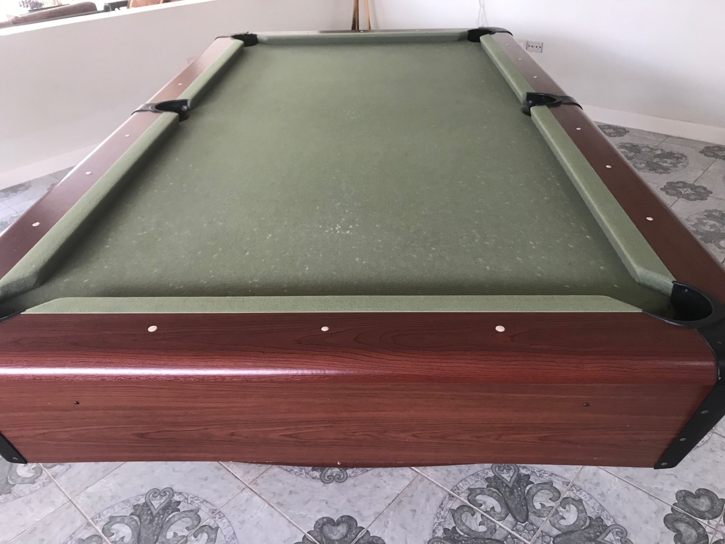 A pool table with a green felt surface and a wooden border.