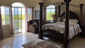 A spacious bedroom with a four-poster bed, large windows, and a view of the outdoors.