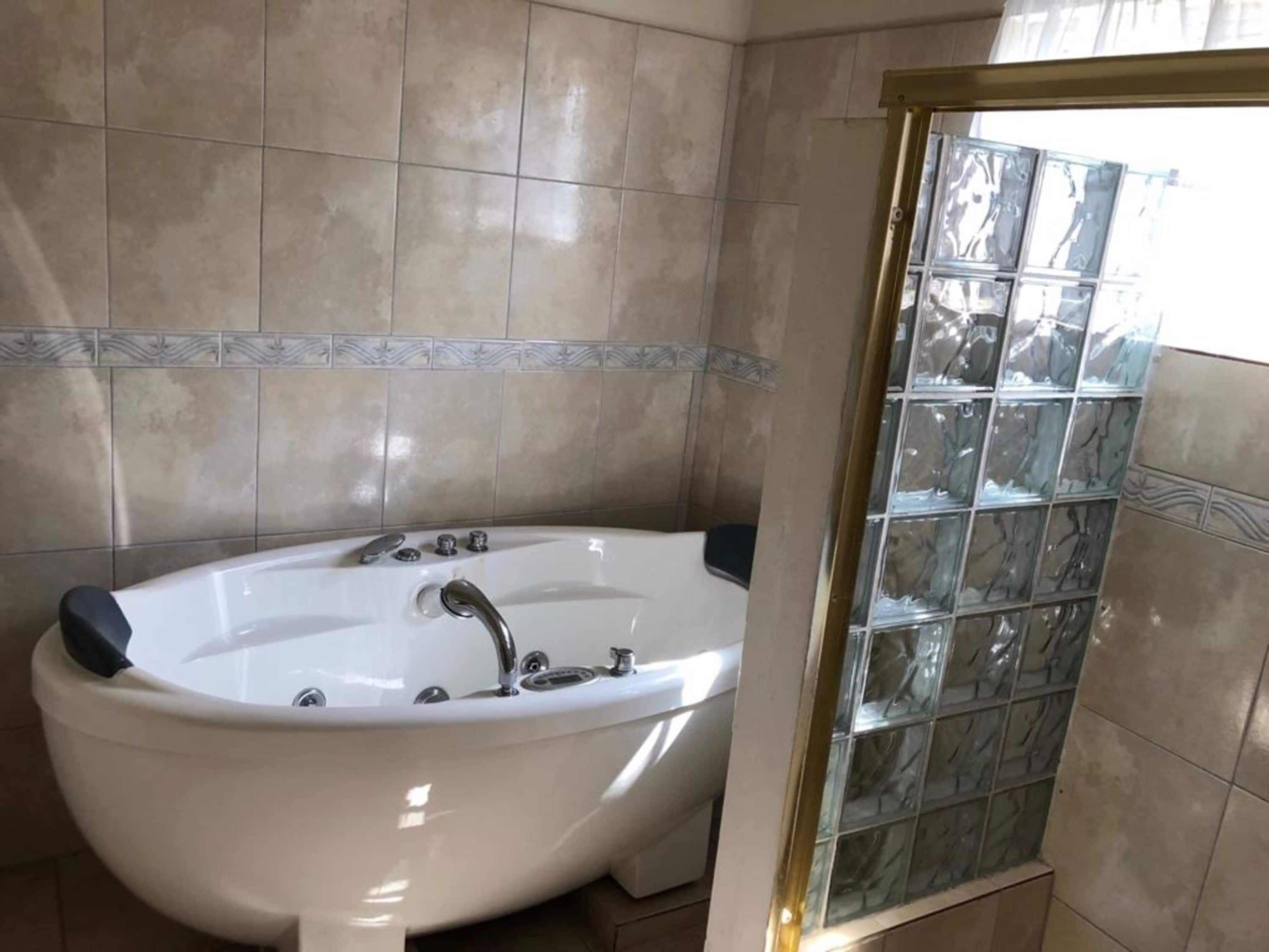 Un baño con bañera independiente, paredes de azulejos y cabina de ducha de vidrio.