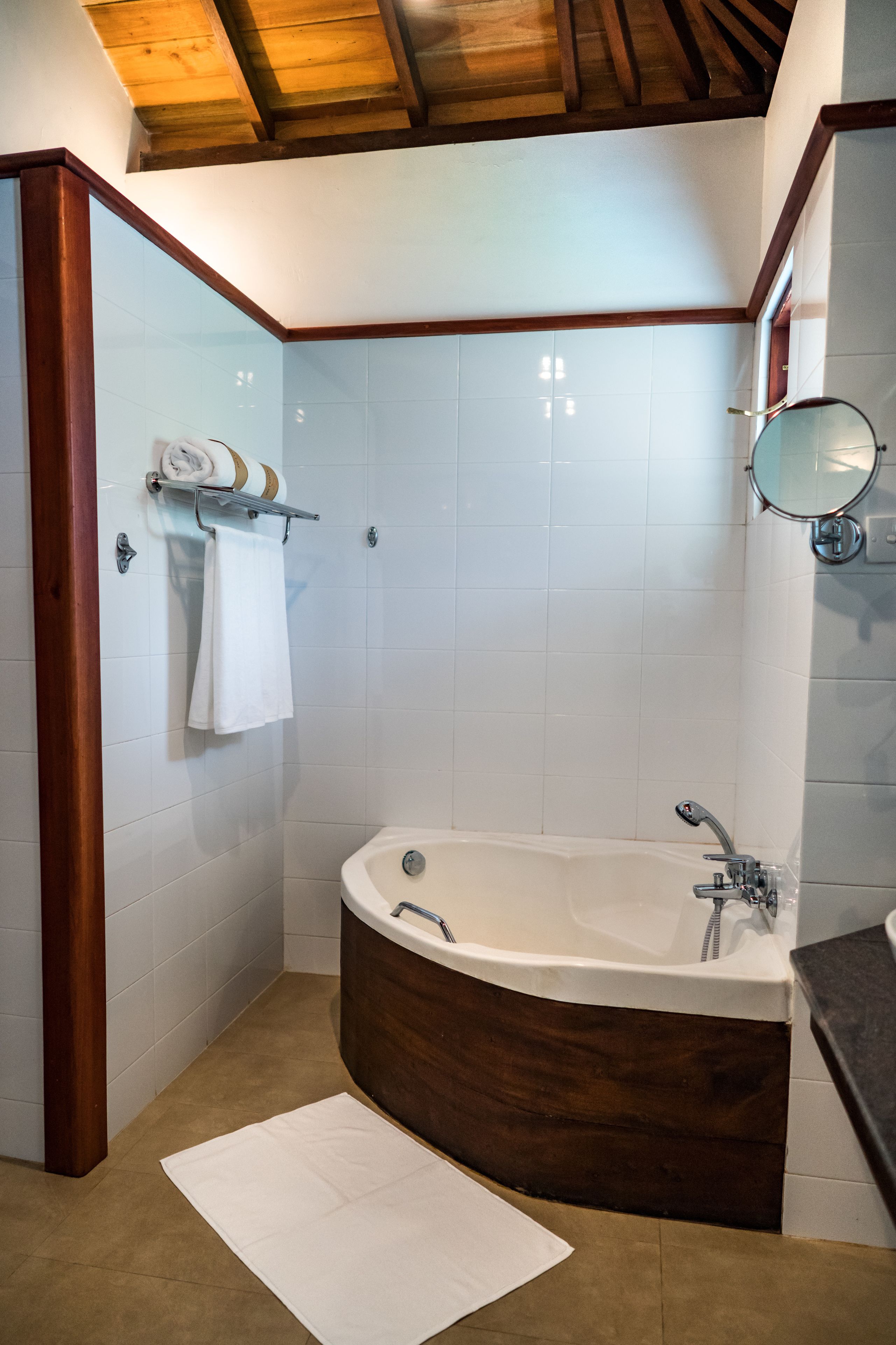 Un baño moderno con una bañera independiente, un tocador de madera y un espejo grande.