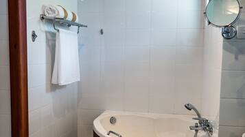 Un baño moderno con una bañera independiente, un tocador de madera y un espejo grande.
