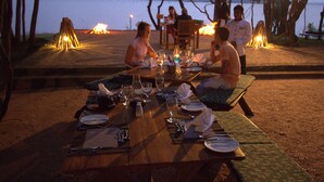 A dining table set outdoors with a view of a lake and mountains in the background. - Amaya Lake Dambulla (Kandalama)