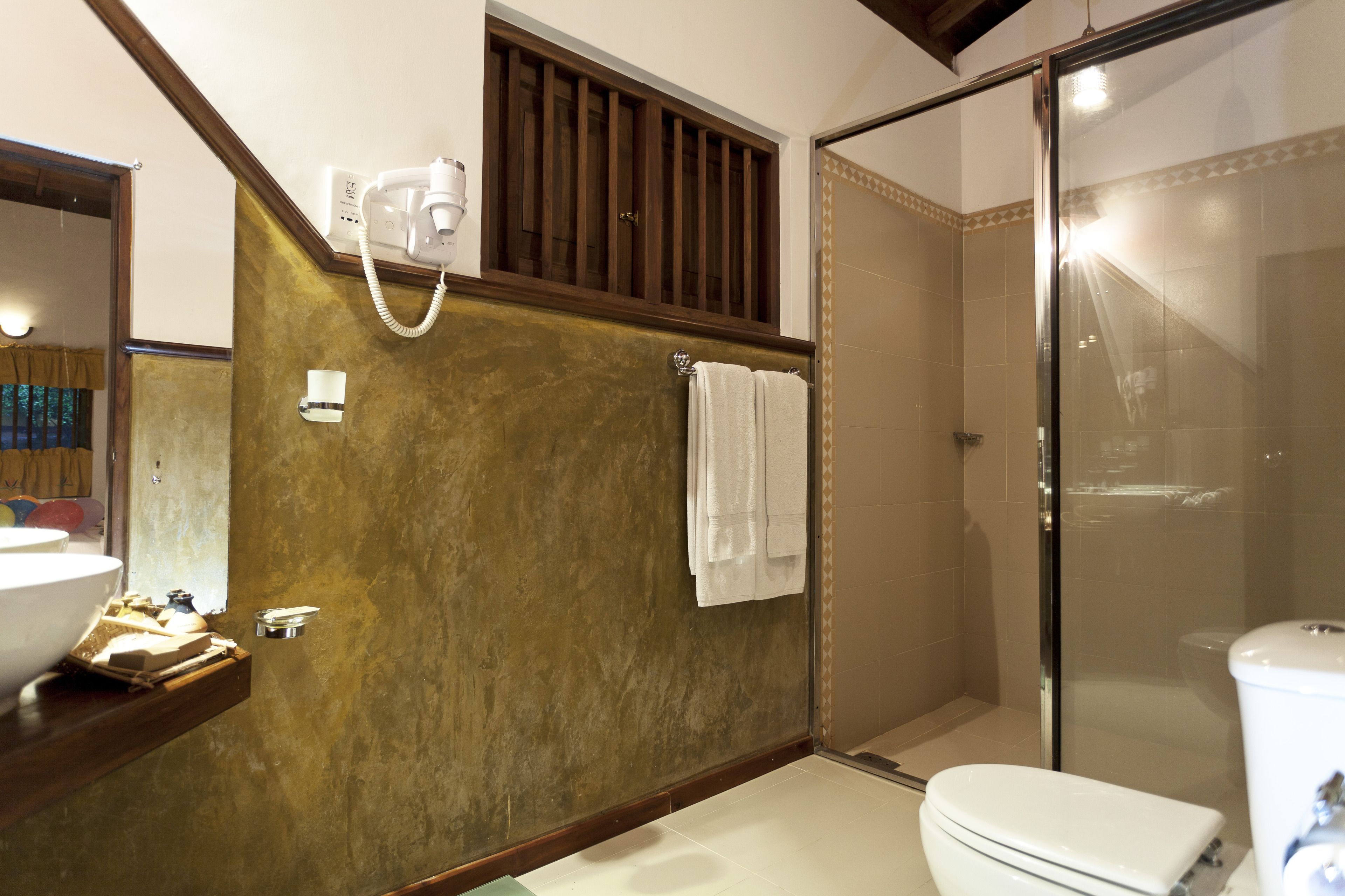 A bathroom with a toilet, a sink, a shower, and a mirror.