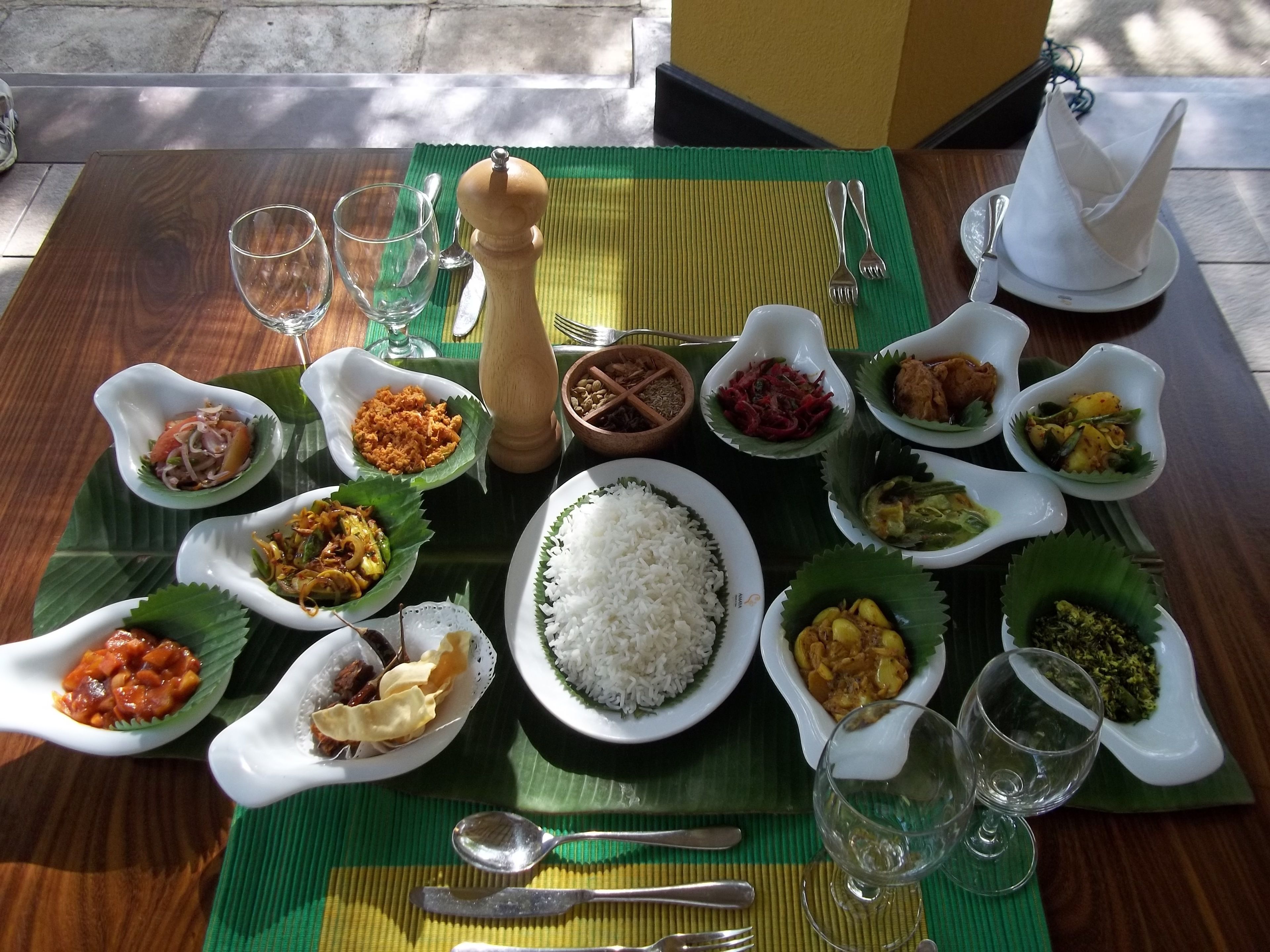 Uma mesa posta com diversos pratos, talheres e copos, dispostos sobre um tapete verde.