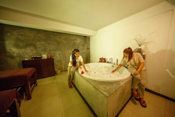 A modern bathroom with a large bathtub, a wooden bench, and a small table. - Citrus Hikkaduwa (Hikkaduwa)