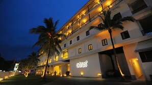 Un hotel de varios pisos con un llamativo letrero que dice 'citrus', palmeras y una fachada bien iluminada.