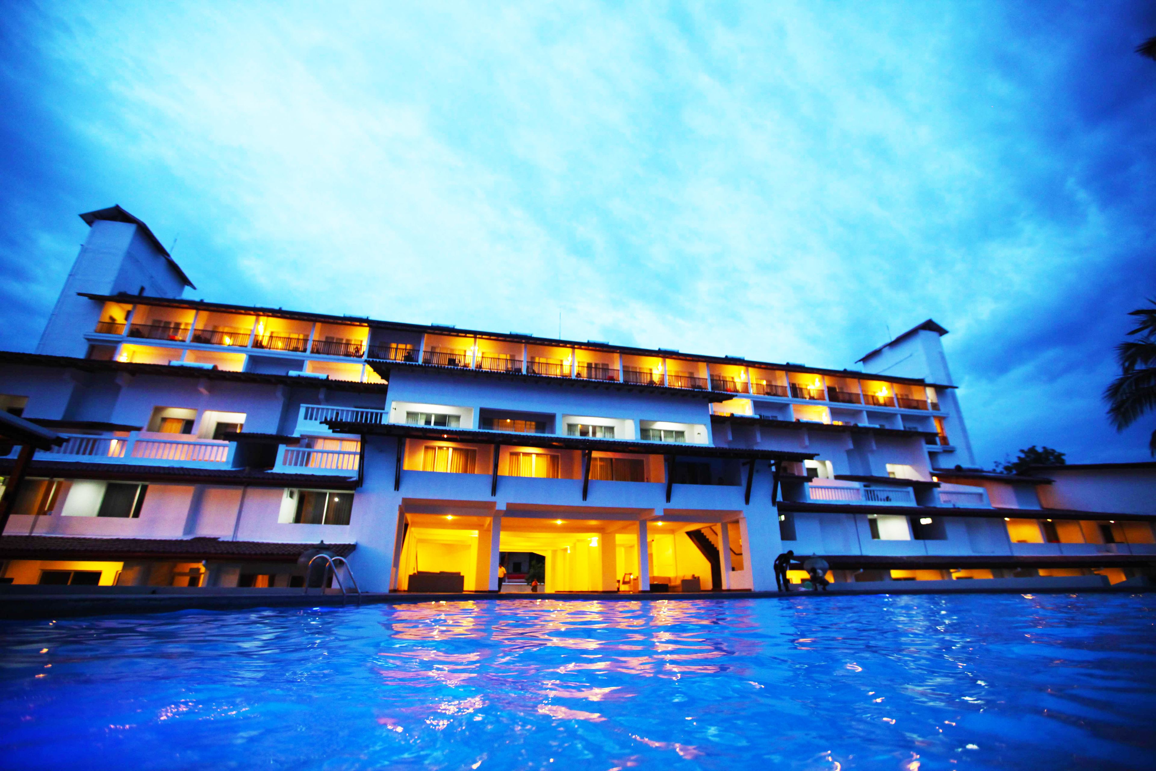 Un hotel a più piani con balconi e una piscina in primo piano.