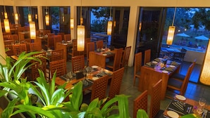 A restaurant with wooden furniture, hanging lights, and potted plants. - Mermaid Hotel & Club (Wadduwa)