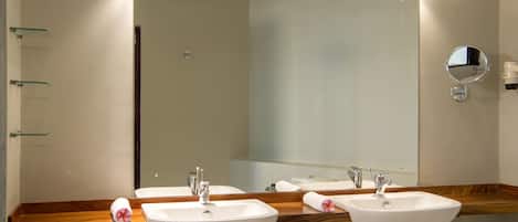A bathroom with two sinks, a large mirror, and a wooden countertop.