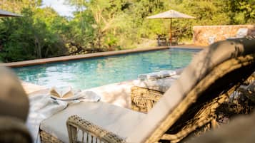 Una piscina al aire libre, sombrillas, sillones reclinables de piscina