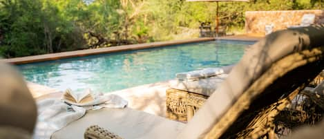 Una piscina al aire libre, sombrillas, tumbonas