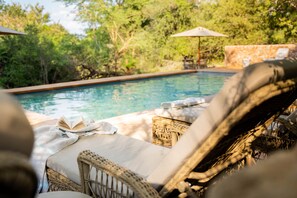 Una piscina al aire libre, sombrillas, sillones reclinables de piscina