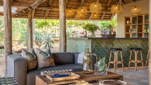 Un espace de détente extérieur accueillant, avec un canapé, une table basse en bois et un bar avec des tabourets.