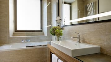 Une salle de bain moderne avec une baignoire, un lavabo, un miroir et une fenêtre.