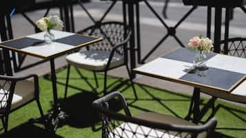 Outdoor cafe tables with chairs, each with a vase of flowers.