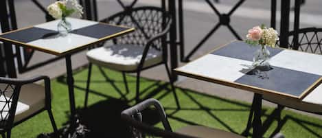 Outdoor cafe tables with chairs, each with a vase of flowers.