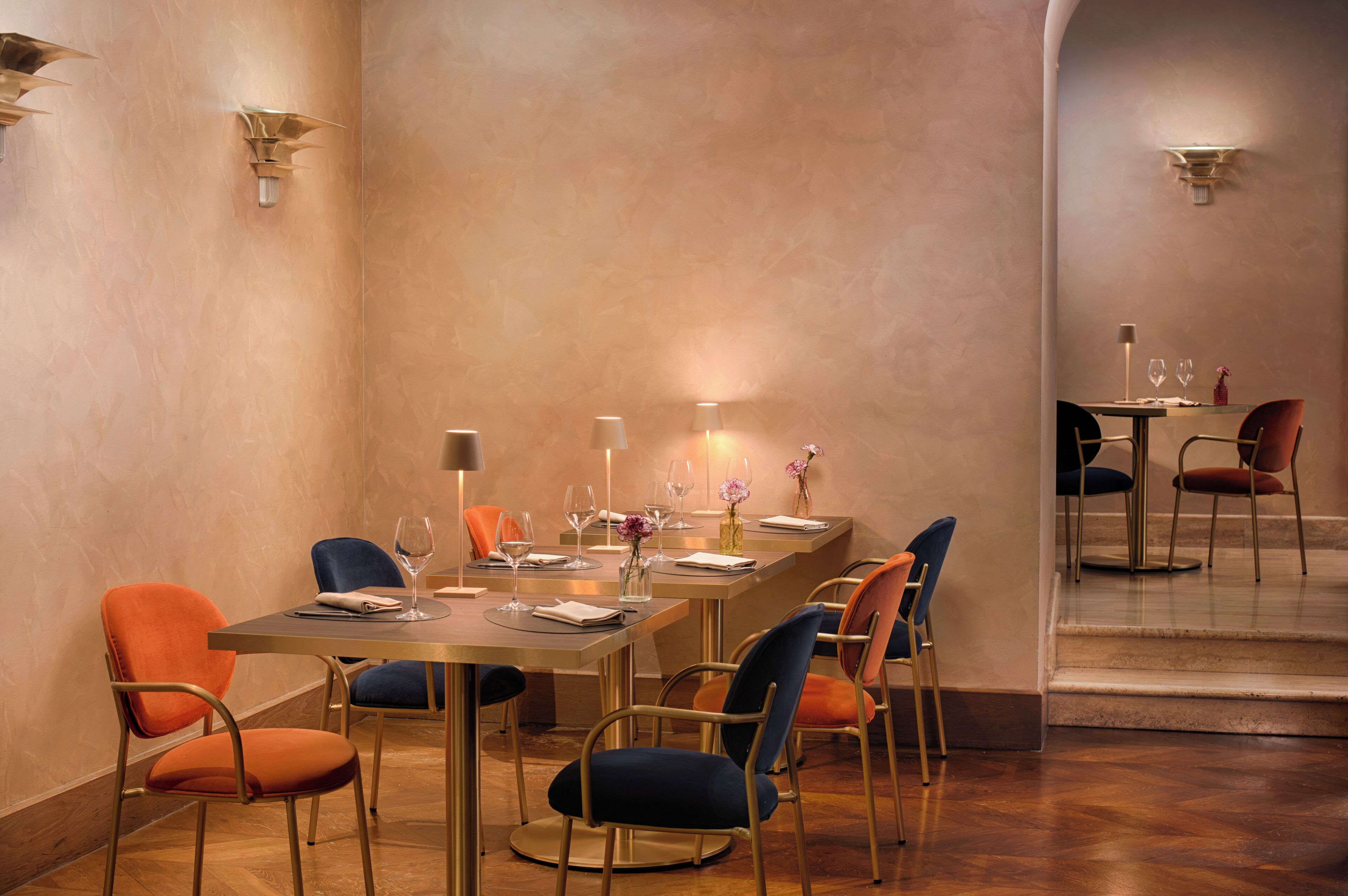 A dining area with a long table, multiple chairs, and wall-mounted lighting fixtures.