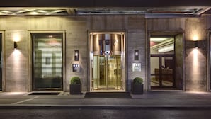 A hotel entrance with numbered doors, a revolving door, and two potted plants.