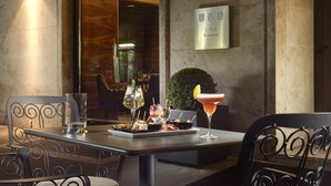 A table with a drink, a glass, and a plate of appetizers at a restaurant.