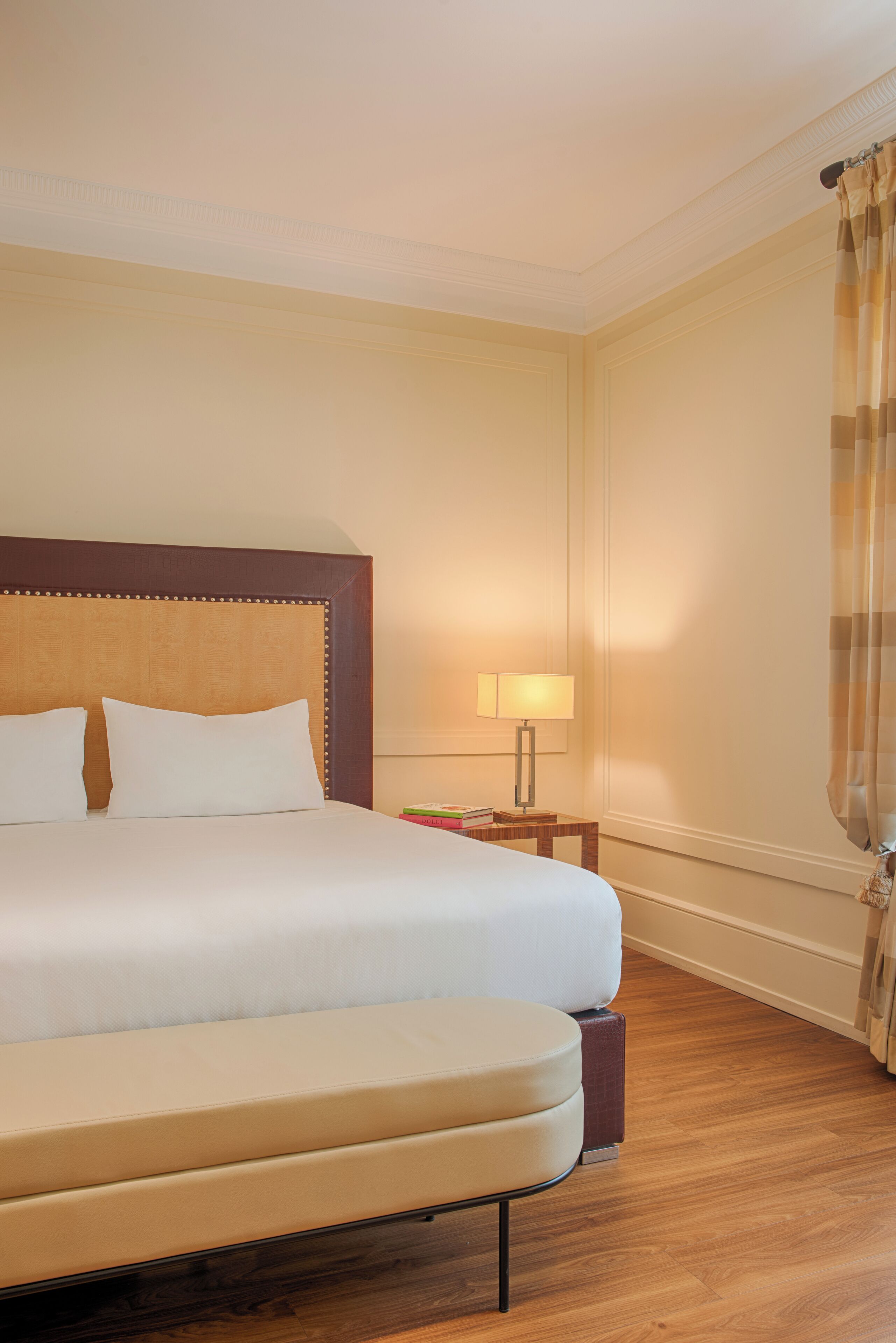 Una habitación de hotel con una cama grande, una mesita de noche con lámpara y una cortina.
