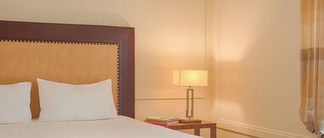 A hotel room with a large bed, a bedside table with a lamp, and a curtain.