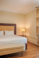 Una habitación de hotel con una cama grande, una mesita de noche con lámpara y una cortina.