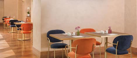 Un comedor de hotel con varias mesas y sillas, un televisor de pantalla plana en la pared y suelo de madera.