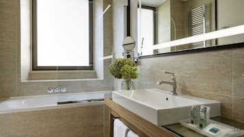 A modern bathroom with a large bathtub, a sink with a mirror, and a window.