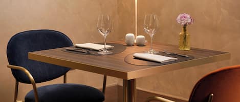 Una mesa de comedor con dos sillas, un florero con flores y una lámpara.