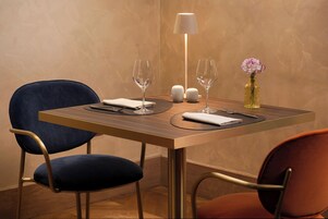 A dining table with two chairs, a vase with flowers, and a lamp.