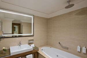A modern bathroom with a large mirror, a sink, a bathtub, and a showerhead.