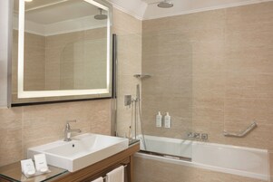 A modern bathroom with a large mirror, a sink, a bathtub, and a shower area.