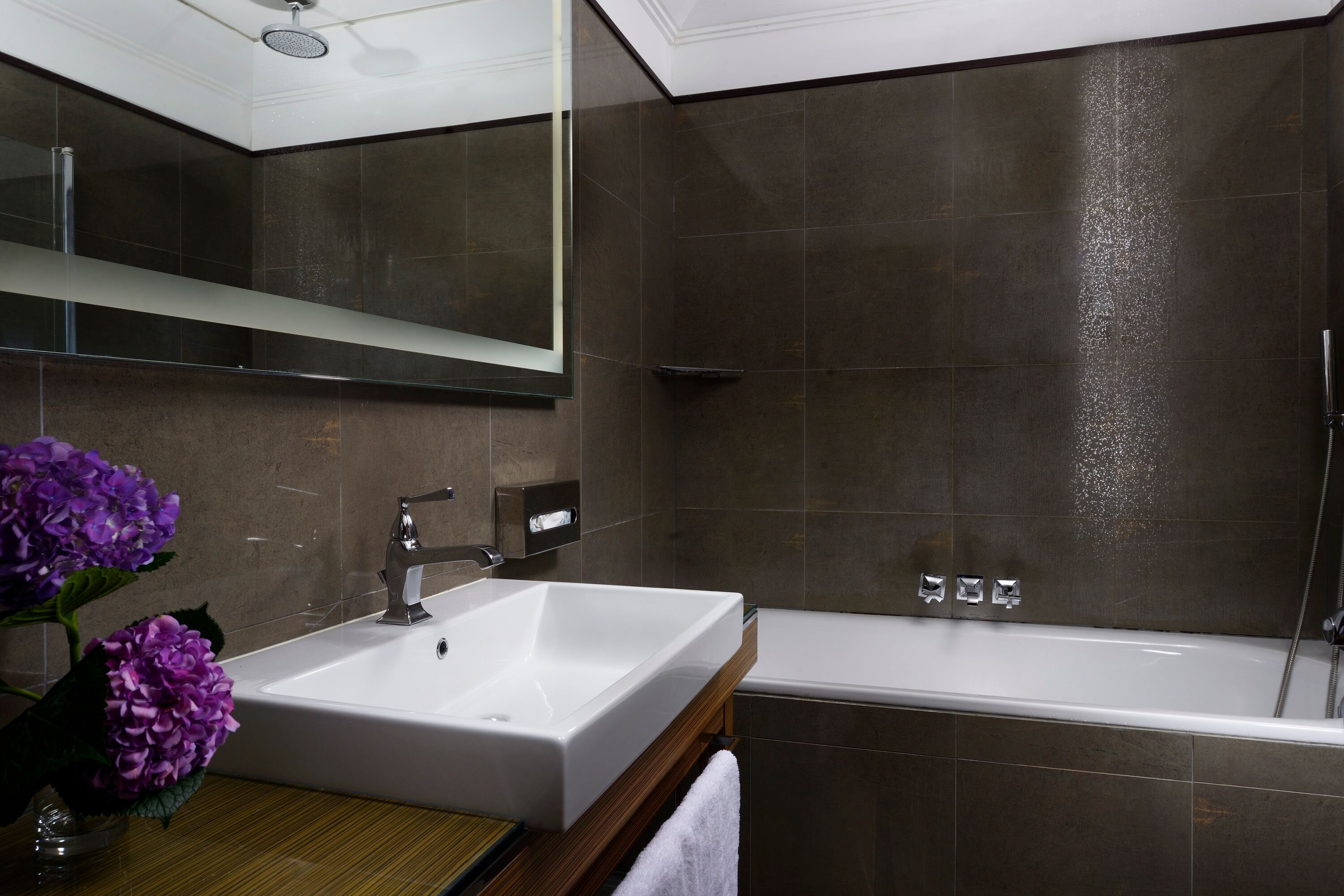 Un bagno moderno con lavandino, specchio e vasca da bagno bianchi.