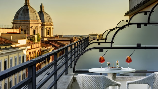 A balcony with a table set for two, overlooking a cityscape with domed buildings.
